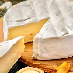 Kawałek sera camembert z białą pleśnią, orzechami i rodzynkami. Czy ser camembert jest zdrowy? W umiarkowanych ilościach może być częścią zbilansowanej diety.