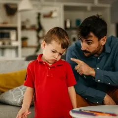 Padre explica a su hijo de 5 años cómo educar con paciencia, mientras el niño muestra una expresión de desánimo.