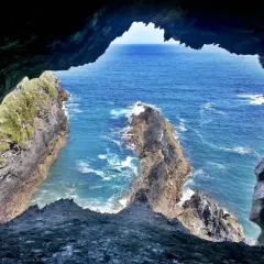 Vista desde la Cova da Doncela hacia el mar azul y acantilados rocosos.