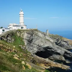 El faro de Cabo Mayor se alza sobre acantilados rocosos, vigilando el azul mar Cantábrico.