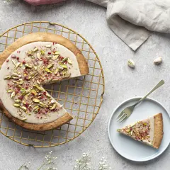 Mazurek stary przepis z pistacjami i malinami, udekorowany na złotej kratce.