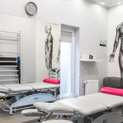 Gabinet fizjoterapii z łóżkami, drabinką, piłką i aparaturą do terapii polem magnetycznym.