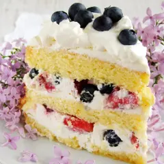 Pyszny, bardzo łatwy tort z mascarpone, przełożony kremem i owocami leśnymi, ozdobiony jagodami i kwitnącym bzem.