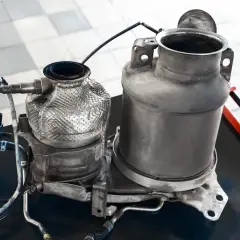 Dwa elementy układu wydechowego Audi, jeden z osłoną termiczną, gotowe do czyszczenia. Zastanawiasz się, ile gram sadzy w DPF Audi?
