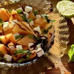 Sałatka z melona, sera feta, mięty i polewy balsamicznej w szklanej misie.