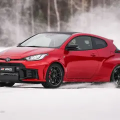 Czerwony Toyota GR Yaris driftuje po śniegu, tworząc obłoki białego puchu.