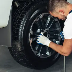 Mecánico revisa un neumático, buscando el precio de reparación de pinchazo.