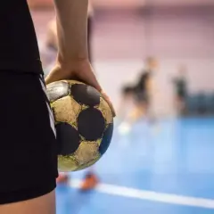 Piłkarz ręczny trzyma piłkę w dłoni na boisku.