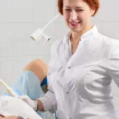 Lekarka bada pacjentkę, która leży na fotelu ginekologicznym. Specjalistka używa sondy USG, by zdiagnozować problemy, takie jak grzybica pochwy.