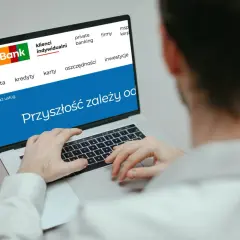 Mężczyzna korzysta z laptopa z logo mBank. Na ekranie widnieje hasło "Przyszłość zależy od..." i opcje takie jak konta, kredyty, karty, oszczędności, inwestycje. To idealne miejsce do zarządzania przelewami mBank.