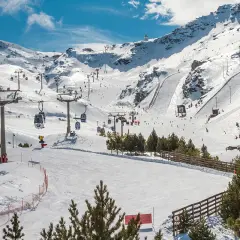 Widok na ośnieżone stoki narciarskie w Sierra Nevada z kolejkami linowymi i narciarzami.