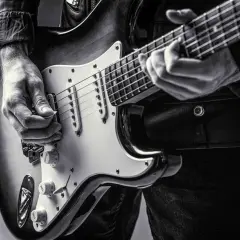 Dłoń gra na gitarze elektrycznej, ukazując klasyczne **marki gitar elektrycznych**.