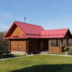Drewniany domek z czerwoną dachem, idealny na wynajem. Możliwa dotacja na taki domek.