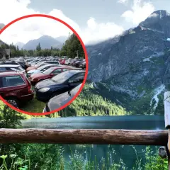 Tłok samochodów na parkingu pod Morskim Okiem. W tle piękne góry i jezioro.