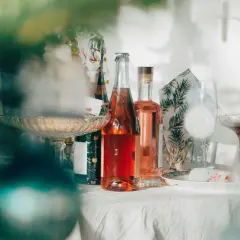 Butelki z różowym winem i kieliszki na stole. Jak zaplanować menu drinków na wesele, ile alkoholu kupić?