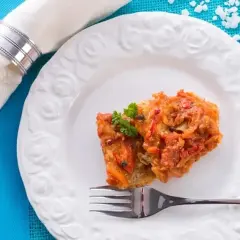 Ryba w aromatycznym sosie do ryby z pomidorami i przyprawami, udekorowana natką pietruszki, na białym talerzu.