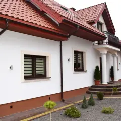 Nowy, biały tynk elewacji lśni na słońcu, podkreślając nowoczesny styl domu.