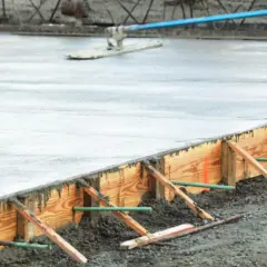Frisch gegossener Beton wird mit einem Abzieher geglättet. Die verlorene Schalung aus Holz hält den Beton in Form, während er aushärtet.
