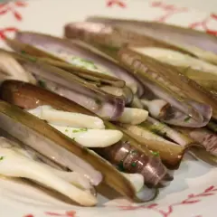 Navajas a la plancha, jugosas y tiernas, servidas con pan y perejil picado. Un manjar marino listo para disfrutar.