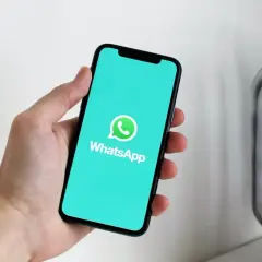 Dłoń trzyma smartfon z logo WhatsApp. Aplikacja istnieje od 2009 roku, więc ma już swoje lata!