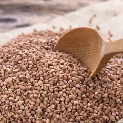 Gryka na worku jutowym, drewniana łyżka zanurzona w ziarnach. Sprawdź aktualną gryka cena za kg.