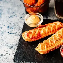 Dwa chrupiące corn dogi na patykach, podane z ketchupem i musztardą. Idealny przepis na corn doga na szybką przekąskę.