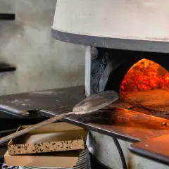 Piec opalany drewnem z żarem w środku. Łopata do pizzy czeka obok, by sprawdzić, ile czasu piecze się pizza.
