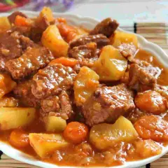 Un plato humeante de estofado de ternera con patatas y zanahorias en una salsa rica y sabrosa.