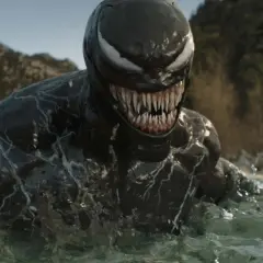 Venom émerge de l'eau, prêt pour la sortie de Venom 4. Le symbiote montre ses dents acérées dans un paysage rocheux.