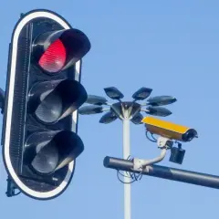 Czerwone światło na sygnalizatorze i żółta kamera monitorująca ruch. Te kamery na sygnalizacji świetlnej dbają o bezpieczeństwo.
