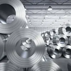 Ogromne zwoje stali kwasoodpornej ułożone w magazynie. Materiał ten jest kluczowy w wielu gałęziach przemysłu.