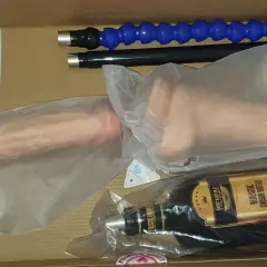 W pudełku leży maszyna erotyczna: dwa realistyczne falusy, butelka imitująca alkohol i dwa giętkie wężyki.