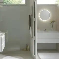 Salle de bain moderne avec douche, meuble vasque, miroir lumineux et dressing ouvert.