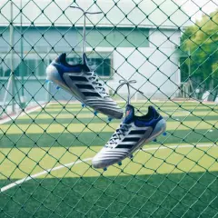 Stylowe buty piłkarskie wiszące na siatce, gotowe na mecz na orliku.