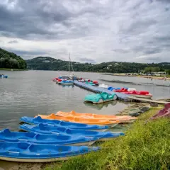 Jezioro Rożnowskie oferuje wiele atrakcji wodnych, w tym kolorowe rowerki wodne i kajaki czekające na plaży i przy pomoście.