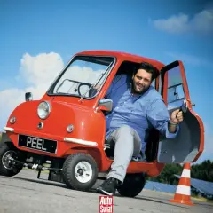 Uśmiechnięty mężczyzna w czerwonym Peel P50. Czy to najtańszy samochód świata?