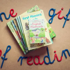 Proste książki po angielsku, idealne do nauki czytania. Stosik kolorowych książeczek i fiszek z napisami "the gift of reading".