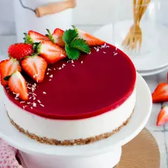 Ein köstlicher veganer Cheesecake ohne Backen, dekoriert mit frischen Erdbeeren und einem glänzenden Fruchtspiegel.