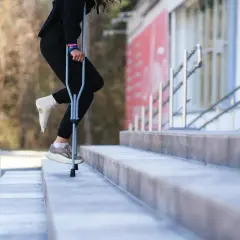Osoba z zabandażowaną stopą porusza się po schodach, używając kul. W której ręce trzymać kulę, by było najwygodniej?
