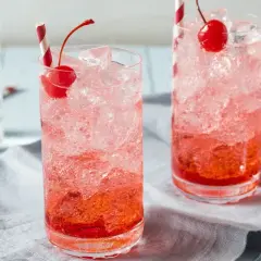 Erfrischende Crodino Rezepte: Zwei Gläser mit Eis, Kirschen und roten Strohhalmen.