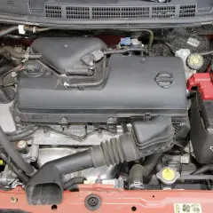Silnik Nissana Micra K12 z widocznym akumulatorem, przewodami i osłoną silnika.