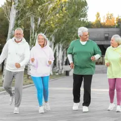 Quatre seniors souriants font du jogging en plein air, une belle illustration des activités pour préparer sa retraite.