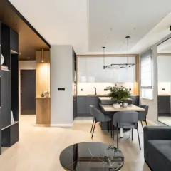 Nowoczesne salon aranżacje: szara sofa, czarna zabudowa, drewniane akcenty i minimalistyczna kuchnia tworzą spójną całość.