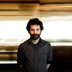 Charlie Kaufman, känd för sina unika filmer, med en drömsk, suddig bakgrund som speglar hans fantasifulla berättelser.