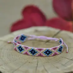 Kolorowa bransoletka z koralików diy, ozdobiona geometrycznym wzorem, spoczywa na drewnianym plastrze.