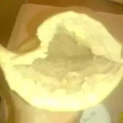 Une main tient un pain libanais ouvert, prêt à être garni. Sa texture moelleuse et sa poche invitent à la gourmandise.