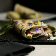 Ein gefüllter Wrap, der zeigt, was sind Tortillas: dünne Fladenbrote, gefüllt mit Hühnchen, Radieschen, Zwiebeln, Käse und Kräutern.