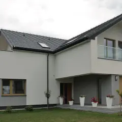 Nowoczesny dom z dwuspadowym dachem i balkonem. Ocieplenie domu wzory tynków w odcieniach bieli i szarości.