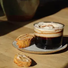 En lyxig kaffedrink med grädde och kanel, perfekt för att baka snabbt fika. Serveras med mandelkakor på ett fat.