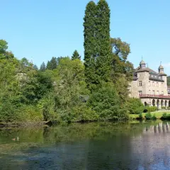 Schloss und Kirche in Wiehl Gummersbach, umgeben von üppigem Grün und einem ruhigen See.